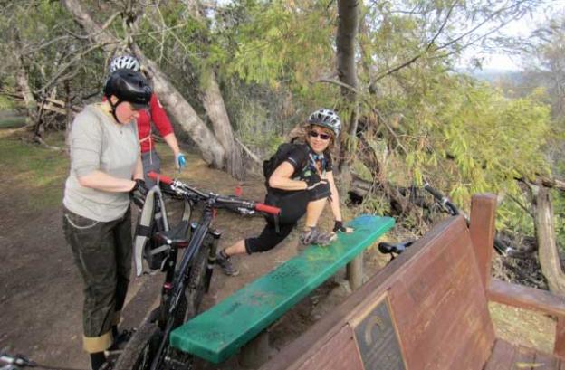 Andrea Lee checks her bike while Karen Kefauver stretches the gams.